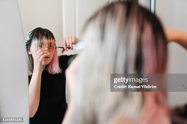 young girl cutting her own hair during lock down - lockdown haircut stock pictures, royalty-free photos & images