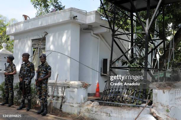 Sri Lankan security forces personnel stand outside amidst toppled iron barricades and a broken wrought iron fence outside the colonial building that...