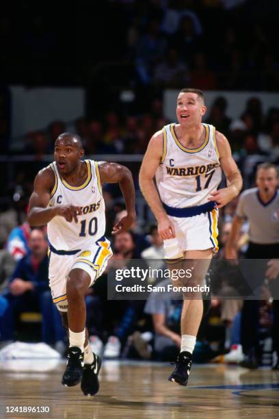 Tim Hardaway and Chris Mullin of the Golden State Warriors run up court during a game in 1991 at The Oakland-Alameda County Coliseum Arena in...