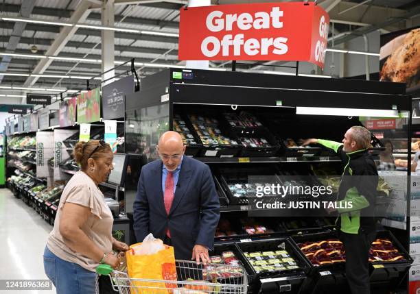 Britain's Chancellor of the Exchequer Nadhim Zahawi speaks to a customer as he looks at her shopping cart, while standing in front of the "Great...