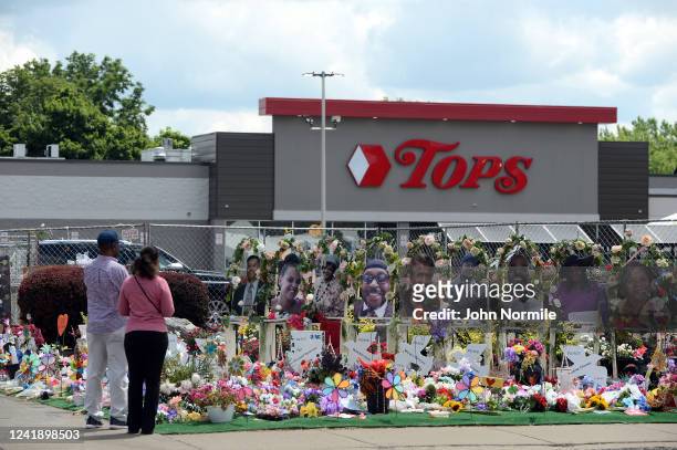 Community members pay respects at a "Memorial Garden" filled with flowers, photos and mementos outside the Tops Friendly Market on Jefferson Avenue...