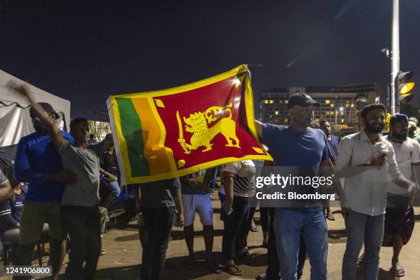 Demonstrators hold up a Sri Lankan flag after hearing news that Gotabaya Rajapaksa, Sri Lanka's president, emailed a letter of resignation, at a...