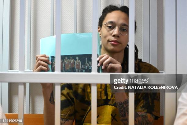 Basketball superstar Brittney Griner sits inside a defendants' cage during a hearing at the Khimki Court in the town of Khimki outside Moscow on July...