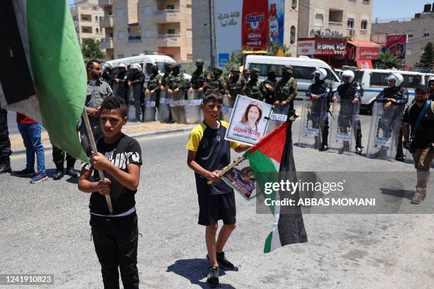 Palestinian security forces stand guard as two Palestinian boys wave national flags during a protest in Bethlehem in the occupied West Bank as US...