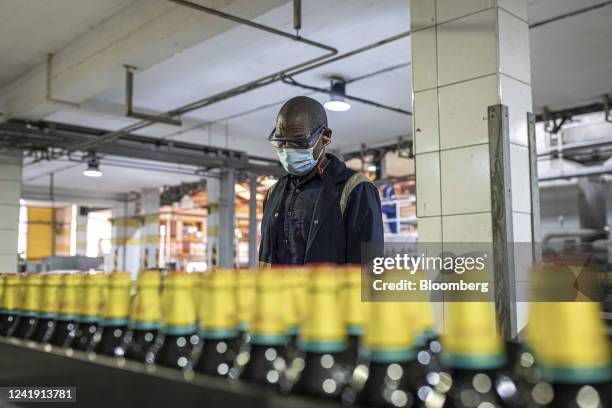 Worker checks bottles of Guinness as they move along a conveyor at the Kenya Breweries Ltd. Bottling plant, operated by East Africa Breweries Ltd.,...