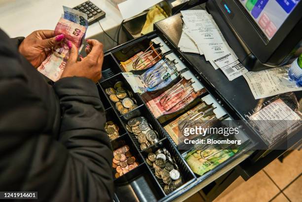 Worker counts out South African rand banknotes for change at the cash register inside a Spar Group Ltd. Supermarket in the Die Wilgers suburb of...
