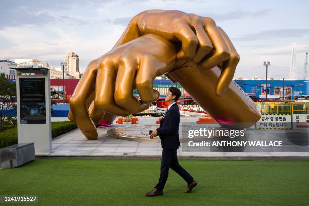 Man walks past a bronze sculpture by artist Hwang Man-seok, modeled after the signature horse-riding hand motion of the "Gangnam Style" song, which...