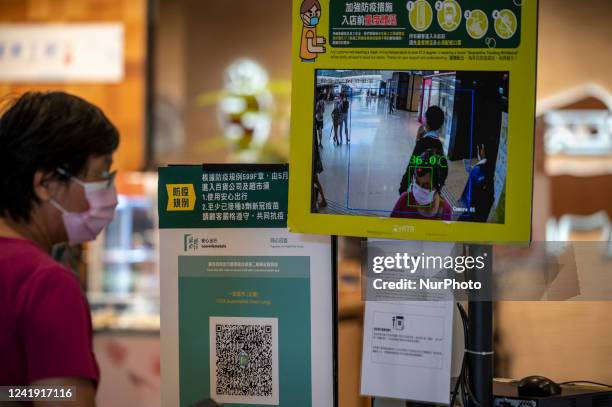 The Leave Home Safe QR code and a temperature check point placed at the entrance of a store inside a shopping mall on July 15, 2022 in Hong Kong,...