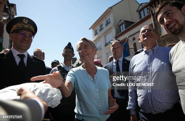 France's Prime Minister Elisabeth Borne is offered a bread by a baker as she walks during a meeting with officials from national police, firefighters...