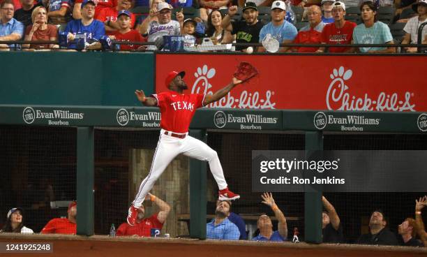 Adolis Garcia of the Texas Rangers leaps to catch a foul ball off the bat of Eugenio Suarez of the Seattle Mariners during the first inning at Globe...