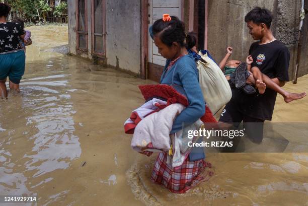 Residents wade through floodwaters in Bekasi on July 16, 2022.