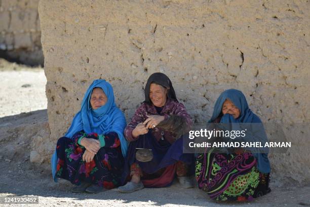 Afghan women spin wool into yarn as they sit near their house in Paytaw village of Yakawlang district of Bamiyan province on July 15, 2022. / "The...