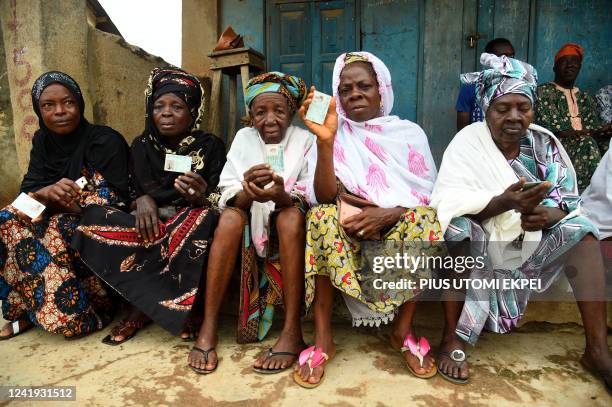 Elderly women sit holding their voter's cards at a polling booth during the gubernatorial election at Ede in Osun State, southwest Nigeria, on July...