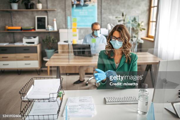 businesswoman putting on protective gloves in the office - bank office clerks stock pictures, royalty-free photos & images
