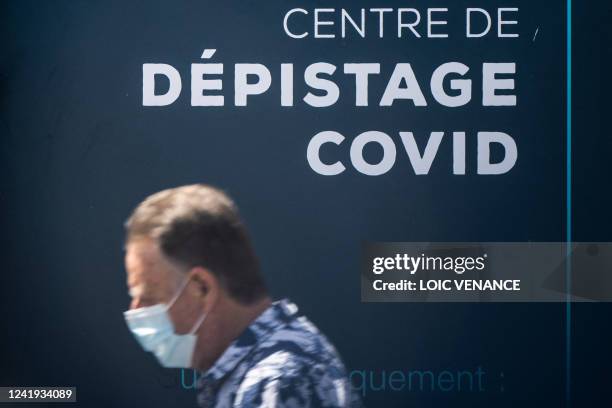 Man wears a face mask as he passes by a Covid-19 testing centre in the city of Nantes, western France, on July 16, 2022. The seventh wave of the...