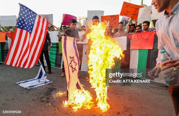 Iranian students from the Islamic Basij volunteer militia burn US and Israeli flags in the capital Tehran, on July 16 2022, during a protest against...