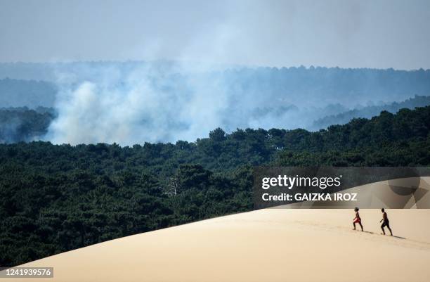 People walk on the Dune of Pilat near La Teste-de-Buch, southwestern France, on July 16, 2022. - The intense mobilization of firefighters did not...