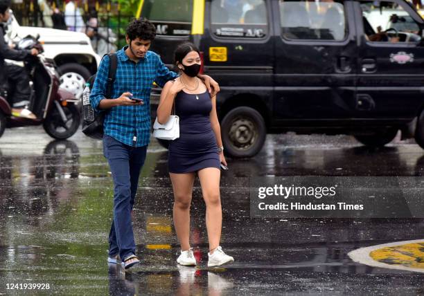 Young couple cross the road in the rain at Chhatrapati Shivaji Maharaj Terminus, on July 16, 2022 in Mumbai, India.