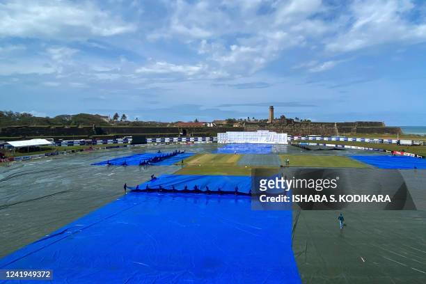 Ground staff cover the pitch as it rains during the second day play of the first cricket Test match between Sri Lanka and Pakistan at the Galle...