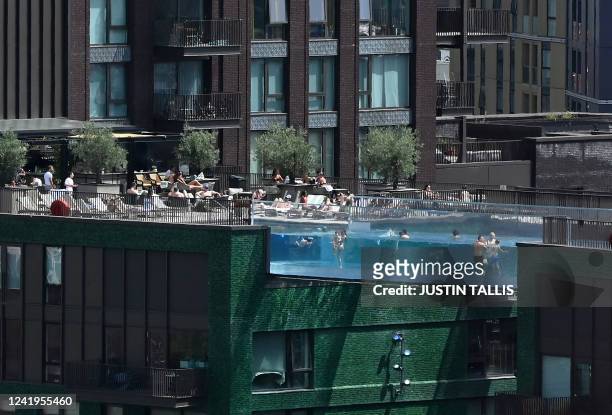 People swim in the Sky Pool, a transparent acrylic swimming pool bridge that is fixed between two apartment blocks, at Embassy Gardens in south-west...