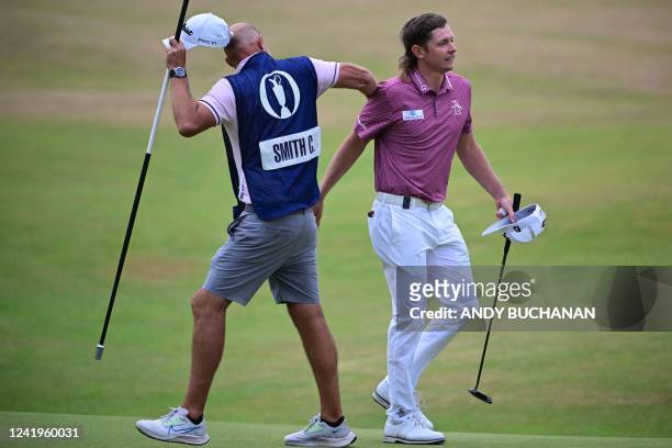 Australia's Cameron Smith is congratulated by his caddie after holing his final putt to make a birdie on the 18th green during his final round 64 on...