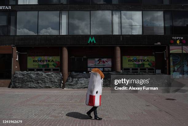 Man in a grilled chicken costume walks by a subway station entrance on July 17, 2022 in Kyiv, Ukraine.