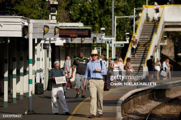 Commuters wait for their train on a platform at West Norwood station in south London on July 18, 2022 amid disruption warnings over extreme heat....