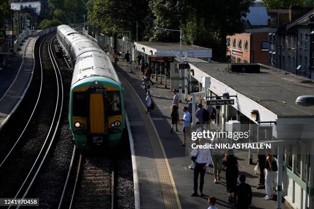 Commuters wait for their train on a platform at West Norwood station in south London on July 18, 2022 amid disruption warnings over extreme heat....