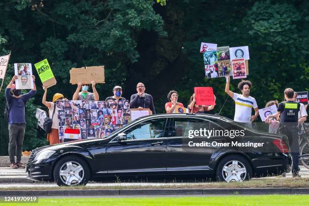 Protesters hold banners and chant slogans against Egyptian President Abdel Fattah al-Sisi as his car passes by them on the way to a meeting with...