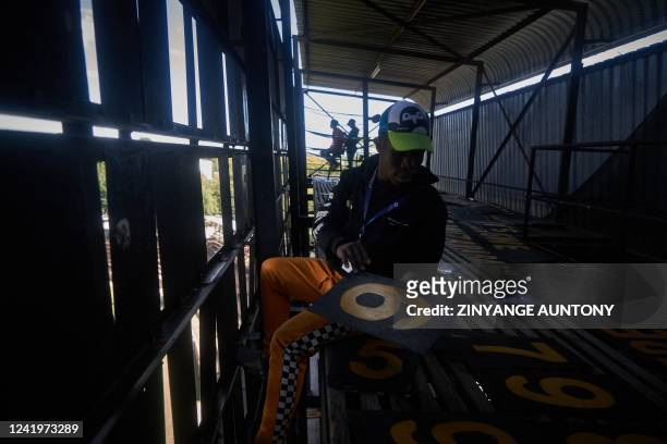 Zenzele Ndebele, a scoreboard operator, swaps numbers from within the manual scoreboard during the cricket T20 World Cup Qualifier tournament at...