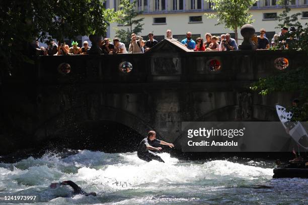 Surfer rides his surfboard on the wave at Eisbach which is an artificial river and also flows for a long stretch through the English Garden in...