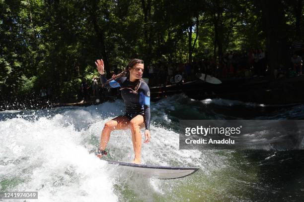 Surfer rides her surfboard on the wave at Eisbach which is an artificial river and also flows for a long stretch through the English Garden in...