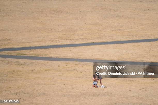 People apply sun cream as they sit in the sun in Greenwich Park, south east London, as parts of England experience heatwave conditions, with the Met...