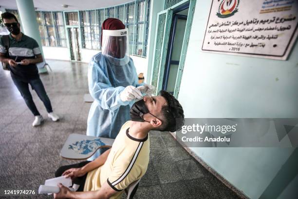 Medical officer assigned by the Palestinian Ministry of Health takes swab samples from the people for the Covid-19 test at Al-Shati Camp in Gaza...