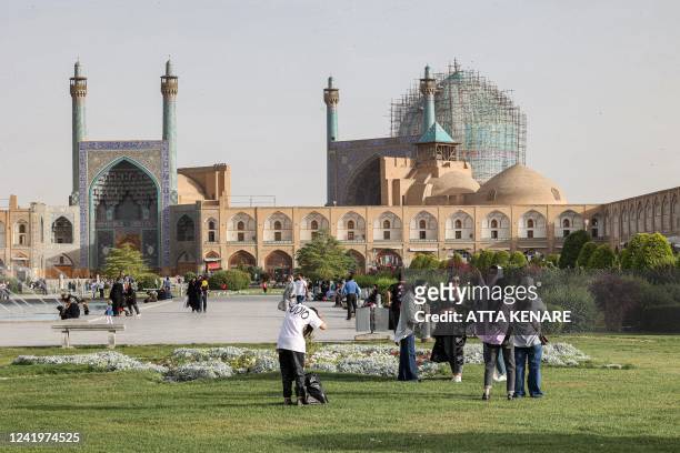 People gather in the garden at the historic Naqsh-e Jahan Square, as the Safavid-built Abbasi Great Mosque is seen in the background, in Iran's...