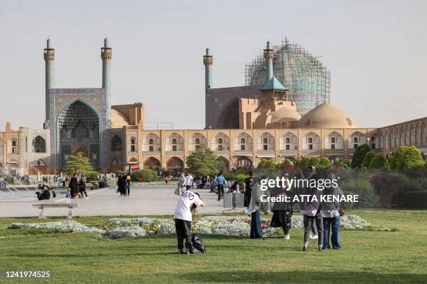 People gather in the garden at the historic Naqsh-e Jahan Square, as the Safavid-built Abbasi Great Mosque is seen in the background, in Iran's...