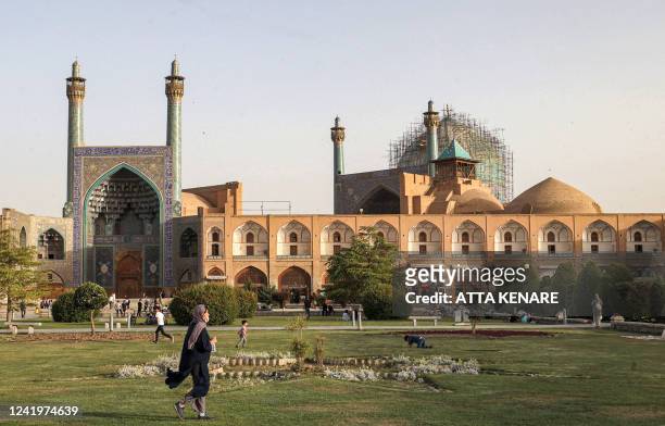 Woman walks in the garden at the historic Naqsh-e Jahan Square, as the Safavid-built Abbasi Great Mosque is seen in the background, in Iran's central...