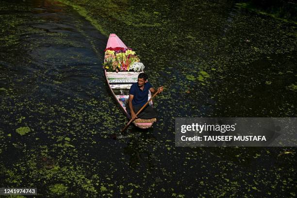 Man carrying flowers on a boat steer through interior channels of the Dal Lake in Srinagar on July 18, 2022.