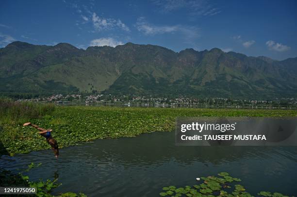 Boy takes a dip into the waters of Dal Lake to cool off on a hot summer day in Srinagar on July 18, 2022.