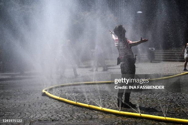 Man cool down with water hoses in the city of Cologne, western Germany, on July 18, 2022 as many parts of Europe experience a heatwave. Europe's...