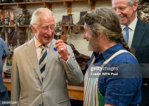 Prince Charles, Prince of Wales uses a magnifying class holds a magnifying glass to the Director of the Copper works, Michael Johnson, as he chats to...