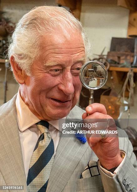 Britain's Prince Charles, Prince of Wales , holds a magnifying glass as he jokes with Michael Johnson during a visit to The Copper Works, a workshop...