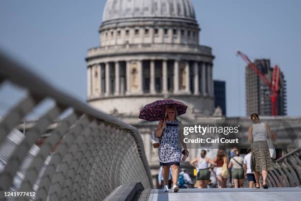 Woman shelters under an umbrella as she walks near St Paul's Cathedral on July 18, 2022 in London, England. Temperatures were expected to hit 40C in...
