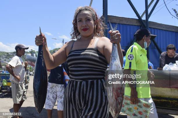 Woman poses for a picture while holding recently caught fish on July 18, 2022 in La Libertad, El Salvador. According to El Salvador's Ministry of...