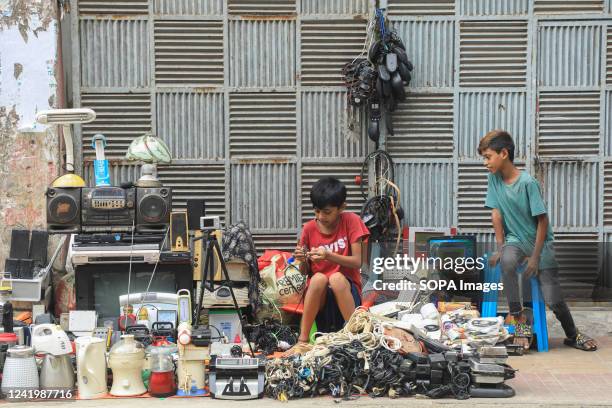 Child is selling old and used electronic products in Dhaka.