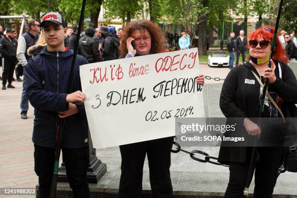 Participants hold a placard that says, "Kyiv congratulates Odessa. Happy Victory Day." during the march of the city's defenders. Dozens of...