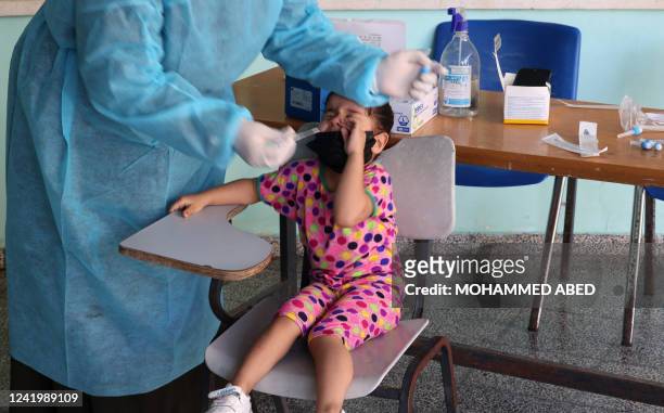 Health worker takes a swab sample from a girl to be tested for the Covid-19 coronavirus, in Gaza City on July 19, 2022.