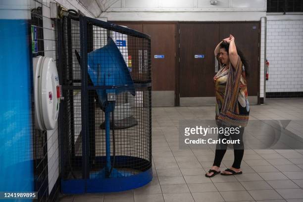 Woman jokingly reacts to the camera by pretending to cool herself in front of a fan in a tube station on July 19, 2022 in London, England....