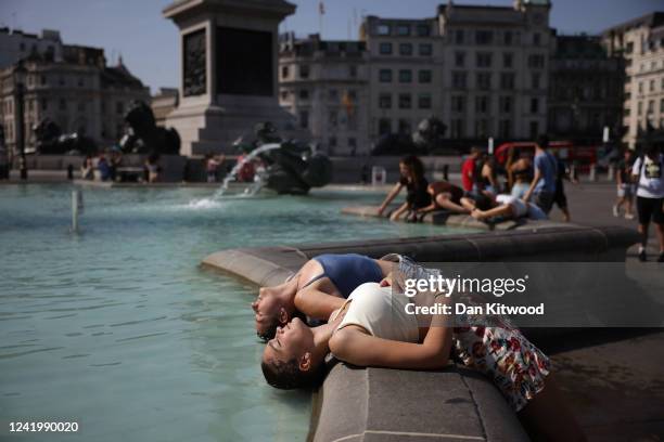 Two women dip their heads into the fountain to cool off in Trafalgar Square on July 19, 2022 in London, United Kingdom. Temperatures were expected to...