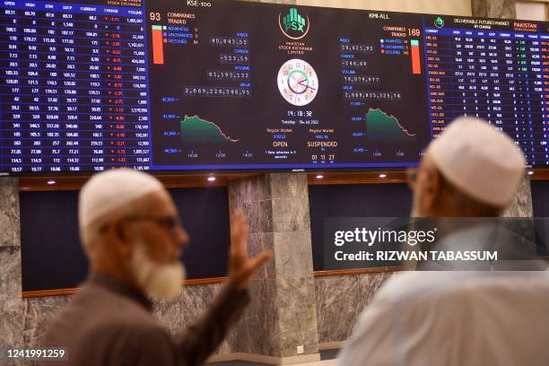 Stockbrokers speak while monitoring the share prices during a trading session at the Pakistan Stock Exchange in Karachi on July 19, 2022.